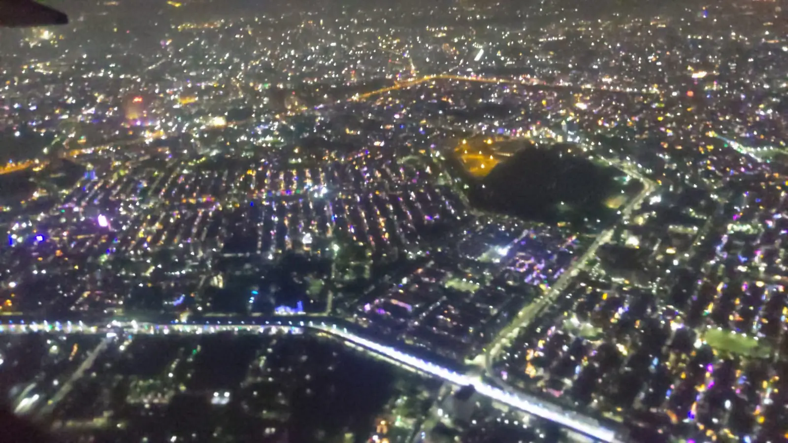 Aerial night view of a city lit up, seen from the aircraft window